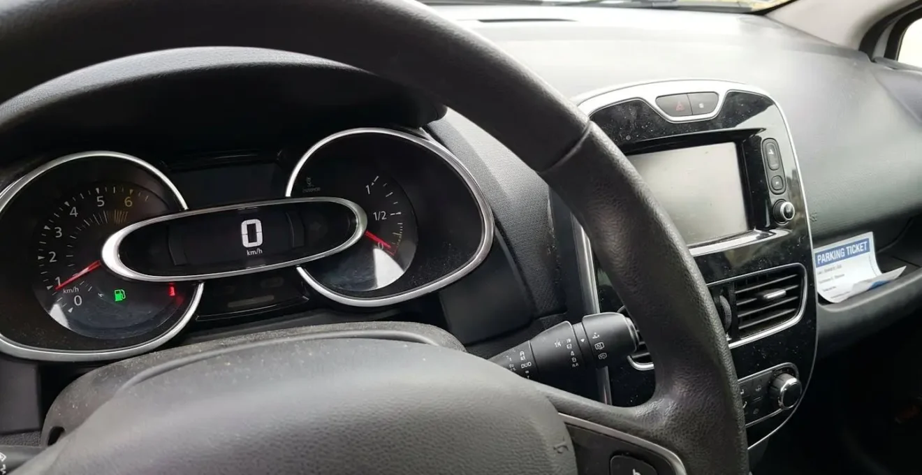 Gros plan du tableau de bord et du volant d'une Renault Clio 4 montrant les compteurs et commandes